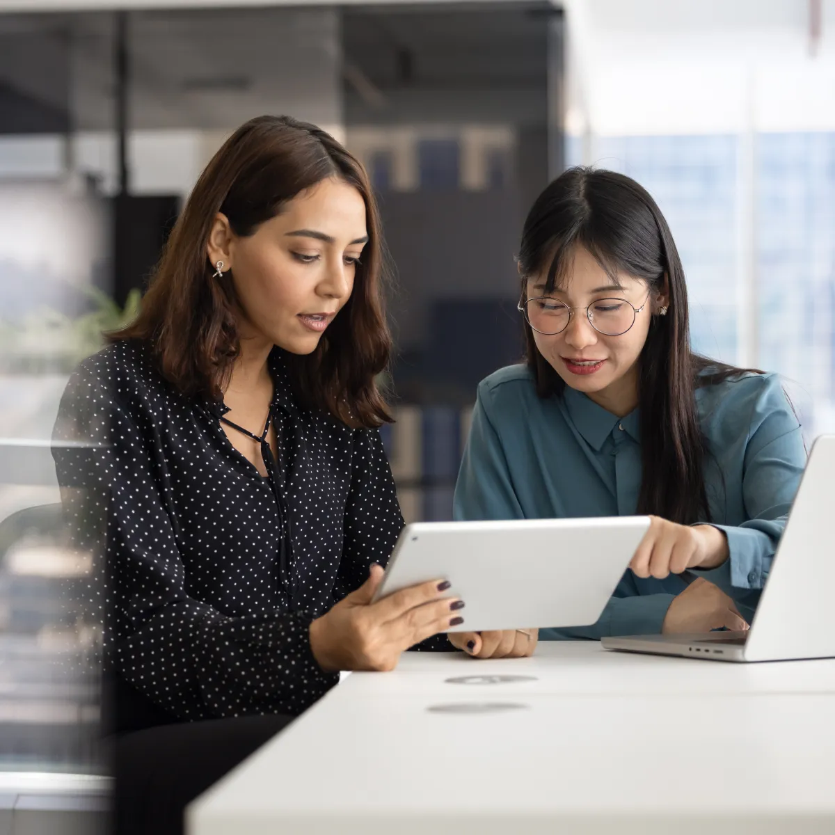 Two tax authority analysts reviewing filings on a tablet