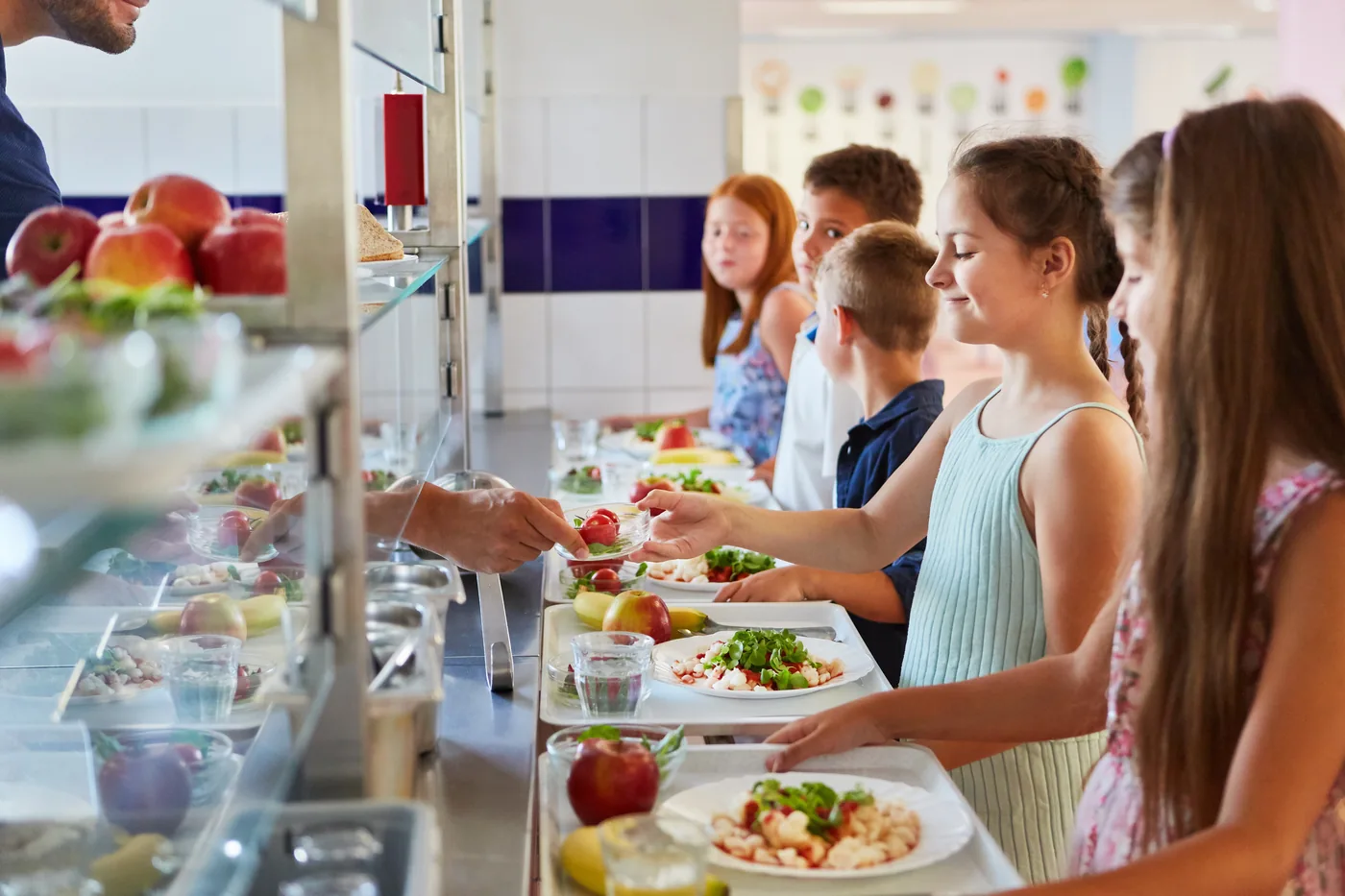 Students being served lunch along a school cafeteria line