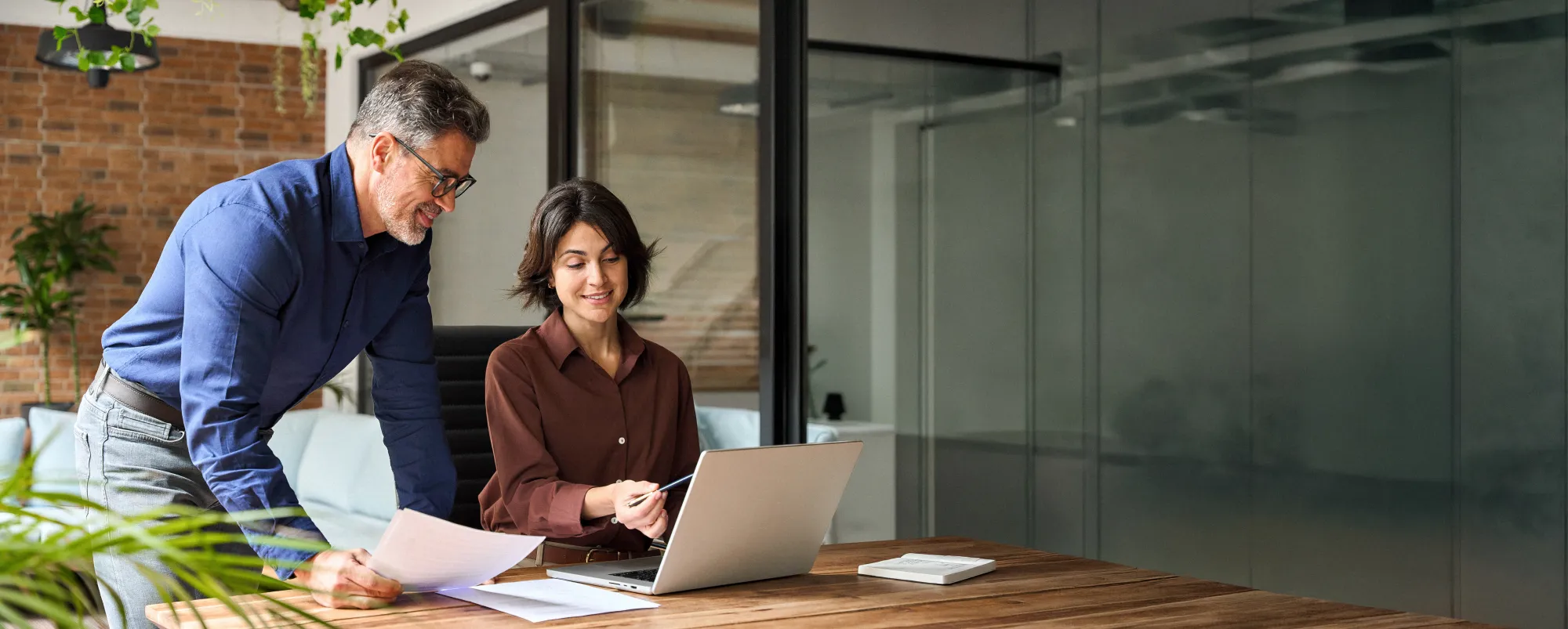 Two colleagues reviewing company filings together at a laptop